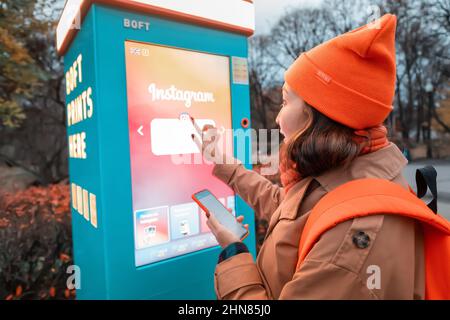 19 octobre 2021, Moscou, Russie: Une femme utilise un kiosque en libre-service pour imprimer des photos depuis son smartphone dans une rue de la ville Banque D'Images