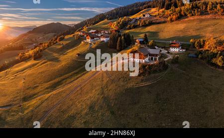 Santa Maddalena, Italie - vue panoramique aérienne du village de Santa Maddalena au coucher du soleil. Paysage d'automne avec maisons tyroliennes traditionnelles, sommets de montagne a Banque D'Images