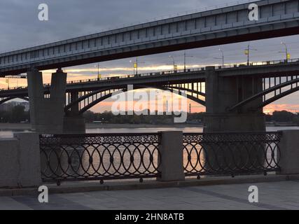 Pont de métro, pont routier voûté au-dessus de la rivière OB à Novosibirsk, la capitale de la Sibérie. La rampe latichée du remblai, le crépuscule du soir Banque D'Images