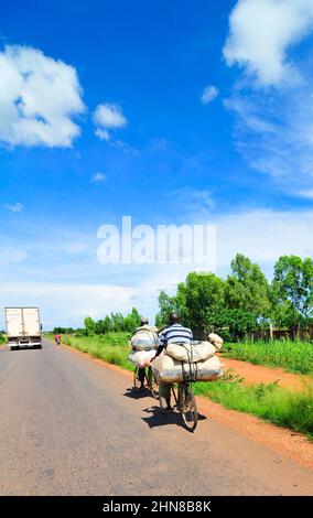 Hommes burkinabés transportant des marchandises sur leur vélo dans le centre du Burkina Faso. Banque D'Images