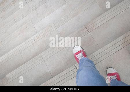Vue rapprochée d'une femme en chaussures rouges qui descend les escaliers. Concept de réduction ou de sortie. Banque D'Images