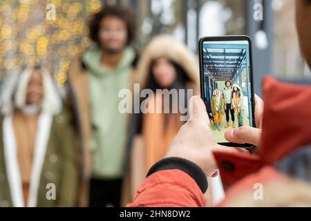 Gros plan de l'homme faisant la photo de ses amis contre le cottage à l'extérieur sur le téléphone mobile Banque D'Images