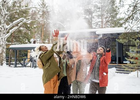 Groupe d'amis heureux jetant la neige dans les airs et s'amuser ensemble pendant les vacances d'hiver en plein air Banque D'Images