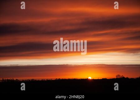 Le soleil se lève sur les Fens près de la ville marchande du Lincolnshire de Bourne, au Royaume-Uni. 15th févr. 2022. Royaume-Uni. Credit: Jonathan Clarke/Alamy Live News Banque D'Images