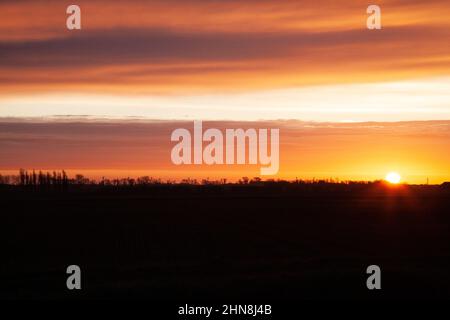 Le soleil se lève sur les Fens près de la ville marchande du Lincolnshire de Bourne, au Royaume-Uni. 15th févr. 2022. Royaume-Uni. Credit: Jonathan Clarke/Alamy Live News Banque D'Images