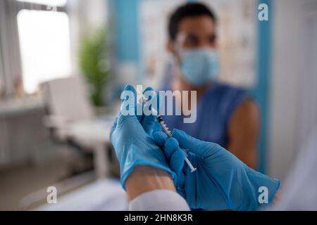 Gros plan d'un médecin tenant une seringue de vaccin Covid-19 et se préparant à la donner à son collègue. Banque D'Images