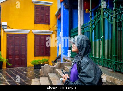 Une femme attend devant une porte de fer dans la vieille ville sous la pluie. Banque D'Images