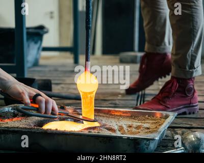 verre fondu versant sur une forme de sable et à la main avec des ciseaux la coupant. Fusion du verre dans un four traditionnel d'une fabrication de souffleur de verre. Fonte de verre Banque D'Images