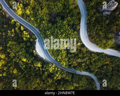 Vue aérienne sur les routes pittoresques en serpentin au milieu d'une forêt dense près des monastères de Meteora en Grèce Banque D'Images