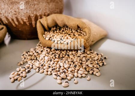 Pile de petits pois yeux noirs ou de haricots blancs ou de cowpeas dans un sac en toile Banque D'Images