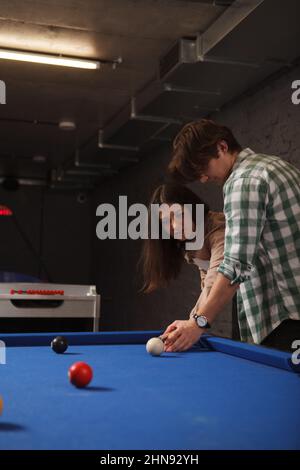 Plan vertical court d'un jeune homme enseignant à sa petite amie jouant au billard Banque D'Images