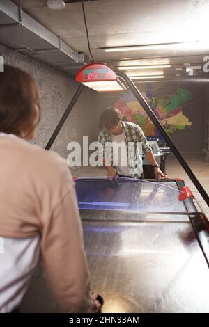 Plan vertical des jeunes s'amusant à jouer sur une table de hockey pneumatique Banque D'Images