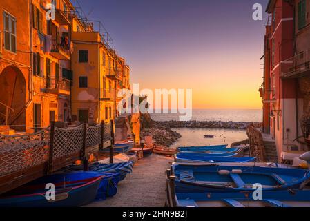 Rue du village de Riomaggiore, bateaux et mer au coucher du soleil, Parc national des Cinque Terre, région de Ligurie, Italie, Europe. Banque D'Images