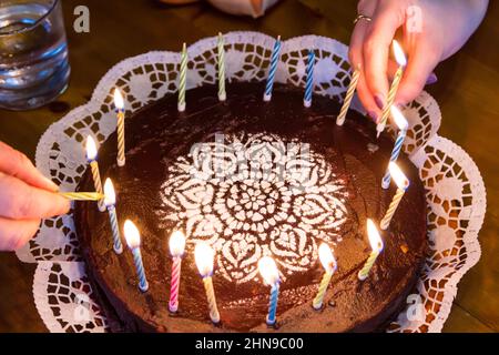 Éclairage bougie d'anniversaire sur gâteau au chocolat avec sucreries sucrées de substitution Banque D'Images
