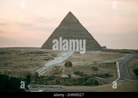 Superbe sphinx et pyramides sous un soleil éclatant. Vue sur le plateau de Gizeh avec les grandes pyramides et le sphinx le soir au coucher du soleil Banque D'Images