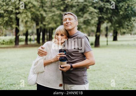 Un couple heureux adulte adulte adulte adulte, amoureux, s'embrassant à l'extérieur dans le parc de la ville.Un homme et une femme blonde de race blanche passent du temps ensemble et boivent du café.Senior Banque D'Images
