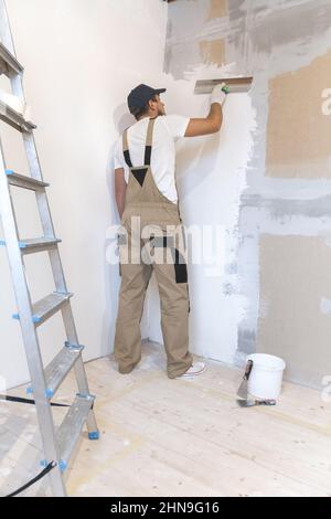 Peintre masculin avec un couteau à mastiquer dans ses mains fait des réparations dans le TH Banque D'Images