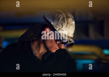 Temirtau, Kazakhstan - 08 juin 2012 : usine de métallurgie d'Arcelor Mittal. Métallurgiste en lunettes de protection noires et casque de sécurité blanc sale. Fabricant d'acier Banque D'Images