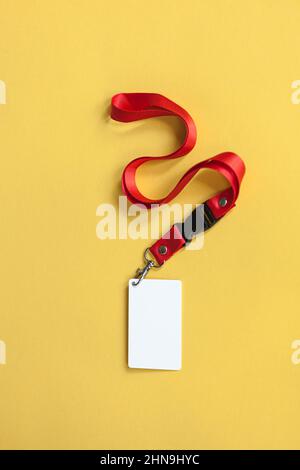 Badge en plastique blanc, cordon rouge avec espace vierge maquette isolée sur fond jaune Banque D'Images