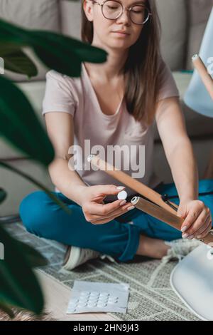 Une femme fixe un tampon de feutre sur la jambe de la chaise, en se souciant du sol Banque D'Images