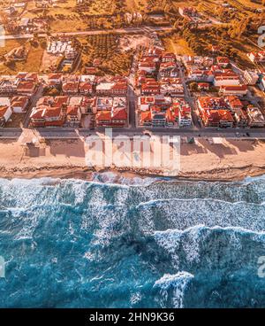 Vue aérienne des maisons et des villas dans une station balnéaire de Sarti à Sithonia, Halkidiki, Grèce avec une plage de sable majestueuse et des vagues de mer pittoresques. Immobilier et Banque D'Images