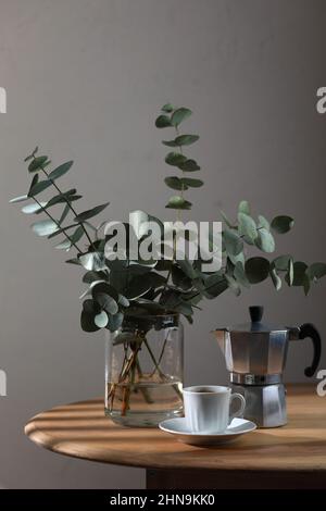 Une tasse de café, une cafetière geyser et un bouquet d'eucalyptus sur une table en bois. Copier l'espace Banque D'Images