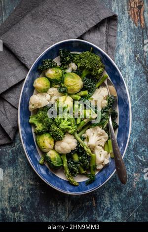 Vue de haut en bas d'un plat ovale de légumes verts cuits à la vapeur et de légumes crucifères. Banque D'Images