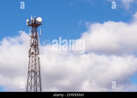 Tour de télécommunications de grande hauteur en structure métallique contre un ciel bleu avec des nuages gris. Arrière-plan. Banque D'Images