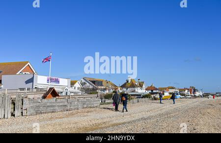 Pevensey Bay vues est Sussex Angleterre Royaume-Uni - Walkers sur la plage avec des maisons donnant sur le front de mer Banque D'Images