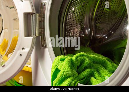 Un lave-linge moderne avec la porte entrouverte et les vêtements à l'intérieur. Concept de blanchisserie à domicile Banque D'Images