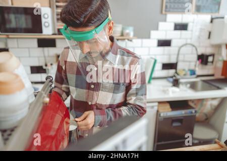 Portrait de l'homme Barista travaillant au café dans la visière protectrice Banque D'Images