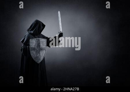 Chevalier foncé avec épée et bouclier dans l'obscurité Banque D'Images