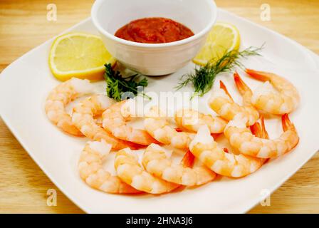 Hors-d'œuvre de crevettes fraîches cuites avec tranches de citron, sauce cocktail, aneth et persil Banque D'Images