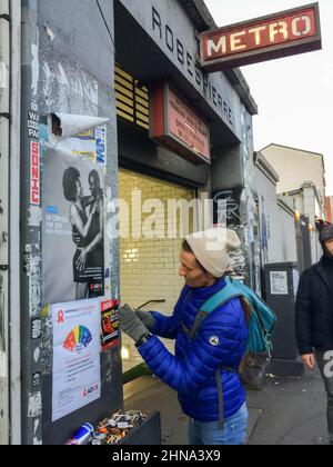 Montreuil France, AIDES Association SIDA, militante affichant des affiches sur le mur à l'extérieur de la station de métro Banque D'Images