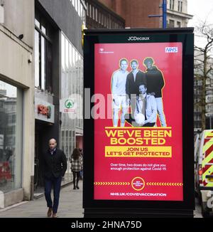 Les gens marchent devant un NHS et HM Government « nous avons été boostés » signe électronique pour annoncer le vaccin de rappel pour combattre Covid-19 à Manchester, Grand Manchester, Angleterre, Royaume-Uni. Le nombre d'infections à Covid-19, à coronavirus ou à Corona continue de diminuer dans le Grand Manchester. 12 364 personnes se sont testées positives dans la région au cours de la semaine se terminant le 8th février 2022, soit une baisse de 35 % par rapport à la semaine précédente. Banque D'Images