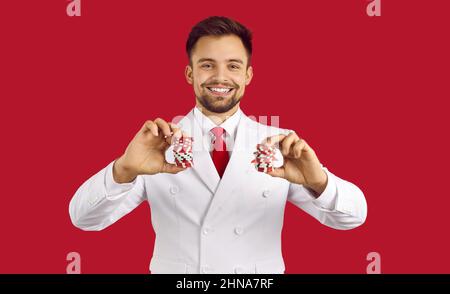 Portrait du jeune homme heureux chanceux en costume tenant des piles de jetons de casino et souriant Banque D'Images