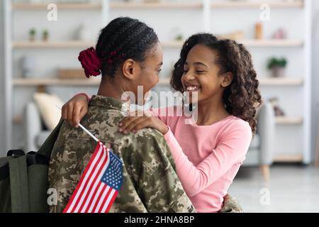 Fille gaie avec drapeau des États-Unis embrassant sa mère Banque D'Images