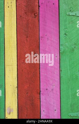 Gros plan des rainures et des marques de scie sur la surface des planches de bois peintes en jaune, rouge, rose et vert. Banque D'Images