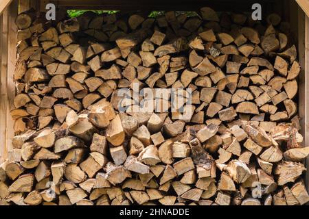 Bois de chauffage empilé stocké dans un abri en bois à conception ouverte. Banque D'Images