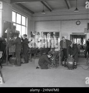 1950s, historique, un certain nombre de jeunes hommes stagiaires ou apprentis dans une aciérie, pays de Galles, Royaume-Uni. Un panneau au-dessus de la porte en gallois dit, 'ymdrech a lwydda', en anglais, signifiant que l'effort fait le succès. Banque D'Images