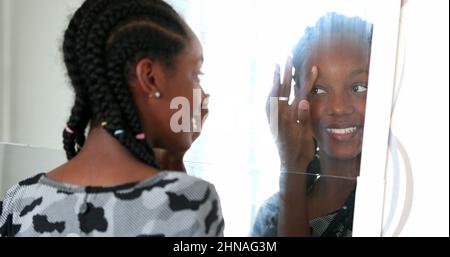 Une adolescente africaine de race mixte s'inspecte devant le miroir Banque D'Images