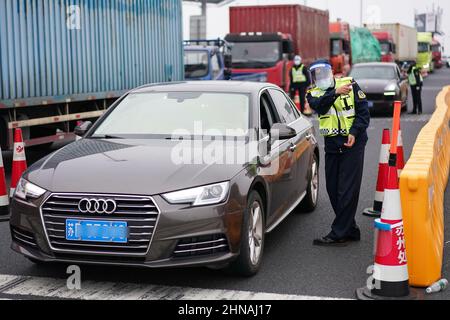 Suzhou, province chinoise du Jiangsu. 15th févr. 2022. Les membres du personnel vérifient les véhicules à la station de péage de Suzhou New District de Beijing-Shanghai Expressway à Suzhou, dans la province de Jiangsu, en Chine orientale, le 15 février 2022. Depuis février 15, Suzhou a fermé 15 entrées d'autoroute et installé 31 points d'inspection de sortie d'autoroute dans toute la ville. Les conducteurs et les passagers doivent porter une preuve des résultats négatifs des tests d'acide nucléique effectués au cours des 48 heures précédentes, ainsi que des codes de santé verts. Credit: JI Chunpeng/Xinhua/Alamy Live News Banque D'Images