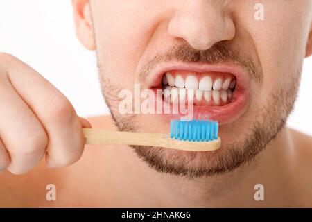 Le sourire d'un jeune homme en gros plan. Un homme tient une brosse à dents dans la main. Le concept de soins buccaux. Banque D'Images