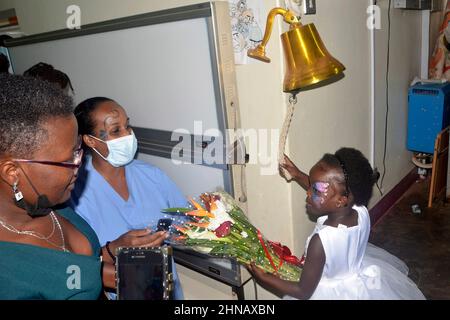 Kampala, Ouganda. 15th févr. 2022. Une infirmière remet un banquet de fleurs à un survivant du cancer pendant une activité pour marquer la Journée internationale du cancer de l'enfance à l'hôpital national d'aiguillage de Mulago à Kampala, en Ouganda, le 15 février 2022. Alors que le monde commémore mardi la Journée internationale contre le cancer de l'enfance, le traitement gratuit des enfants atteints de cancer en Ouganda fait renaître leur espoir. Crédit: Nicholas Kajoba/Xinhua/Alamy Live News Banque D'Images