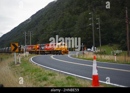 AICKENS, CÔTE OUEST, NOUVELLE-ZÉLANDE, 12 FÉVRIER 2022 : un train de marchandises traverse la route nationale 73 à Aickens, sur la côte ouest, en route vers la mine de charbon Stockton Banque D'Images