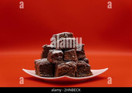 Brownies sur une plaque blanche et un fond rouge Banque D'Images