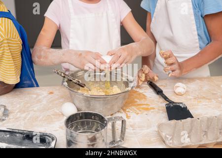 Les enfants se sont rassemblés dans une cuisine moderne et ont étudié une recette de délicieux dessert tout en pensant au menu festif de la fête des mères Banque D'Images