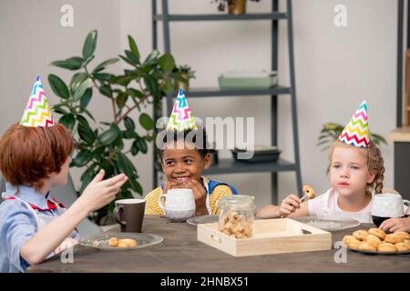 Cute little boy tamisant la farine sur bol en allant faire de la pâte de pâtisserie maison dans la cuisine Banque D'Images