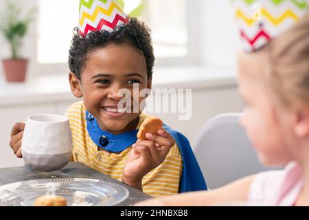 Cute little boy tamisant la farine sur bol en allant faire de la pâte de pâtisserie maison dans la cuisine Banque D'Images