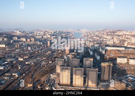 Vladivostok, Russie - 5 février 2022 : Vue d'en haut des maisons et des rues de la ville. À l'horizon, vous pouvez voir la mer et les ponts. Banque D'Images